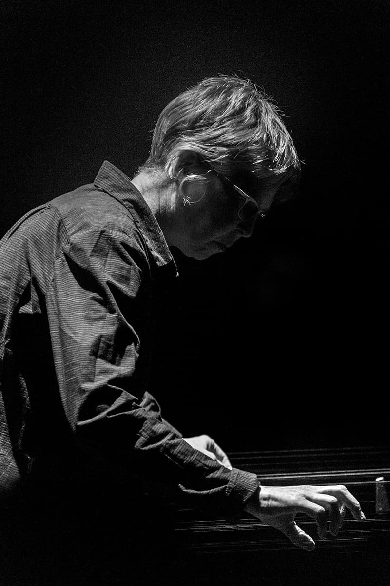 A person is playing a set of suspended metal strings in a dimly lit environment.