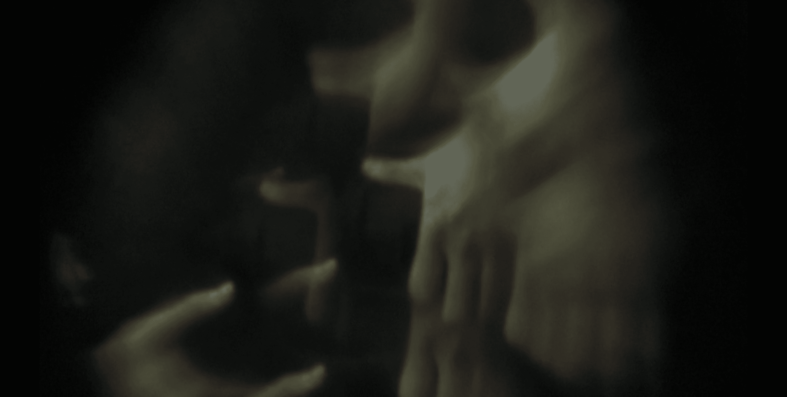 A blurred image showing multiple overlapping hands with a dark background.