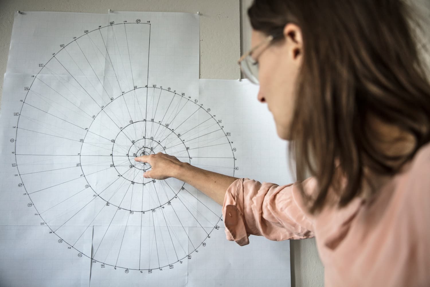 A person points to a spiral diagram on a large sheet of graph paper.