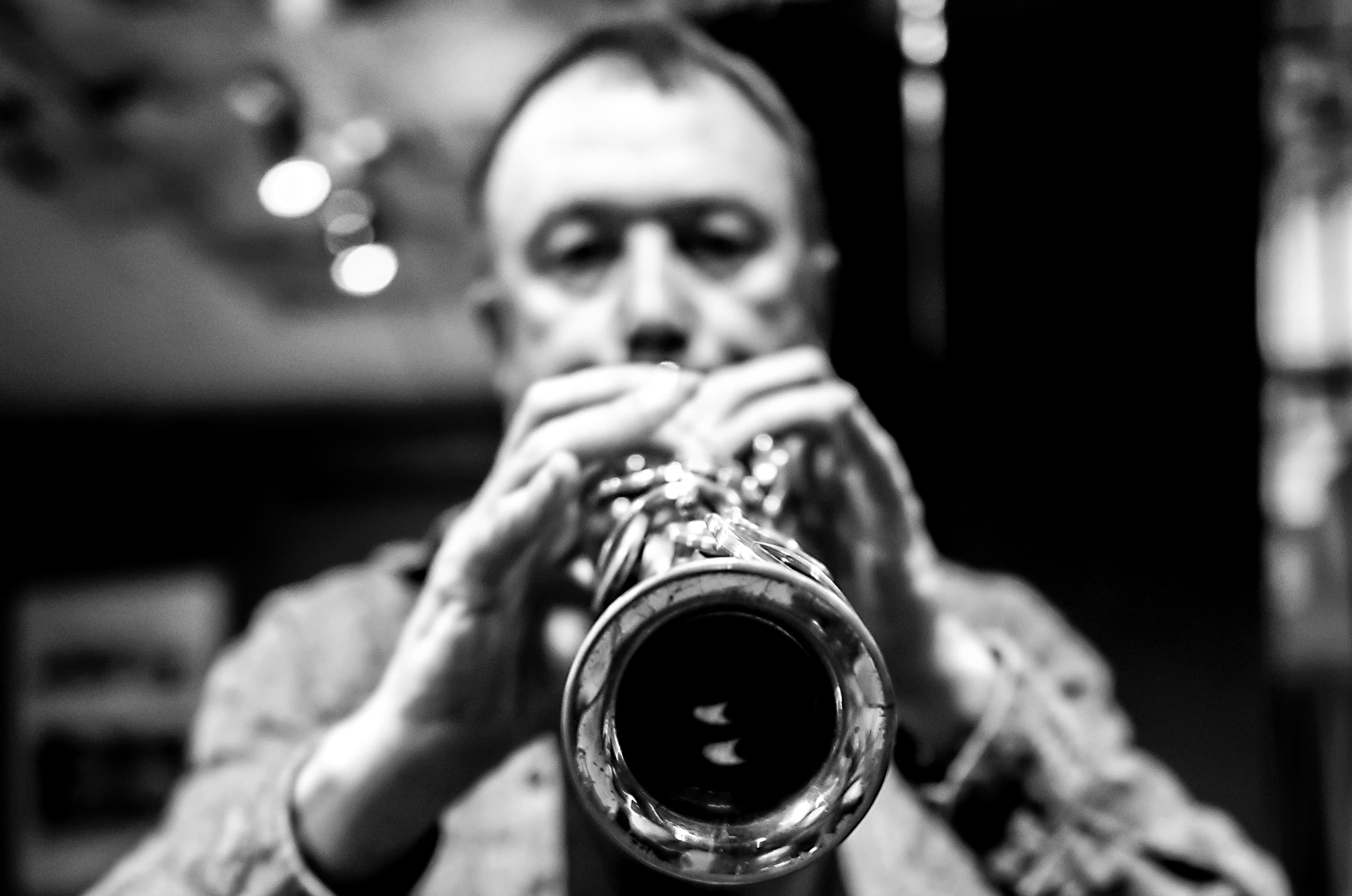 A person is playing a wind instrument, with the focus on the instrument's bell in the foreground.