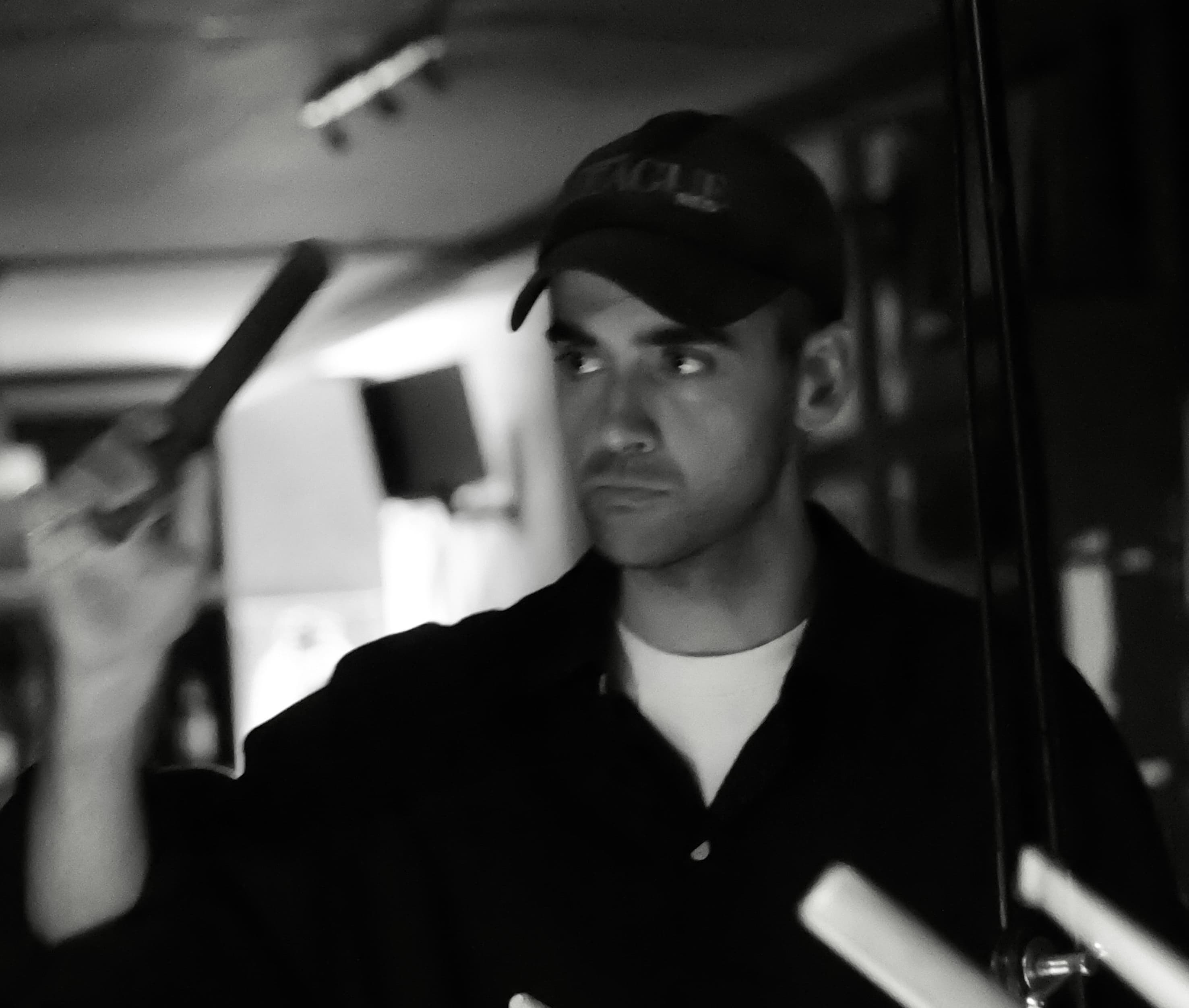 A person in a cap is holding a stick in a dimly lit room.